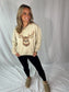 Woman wearing a beige sweatshirt with a deer graphic on a white background
