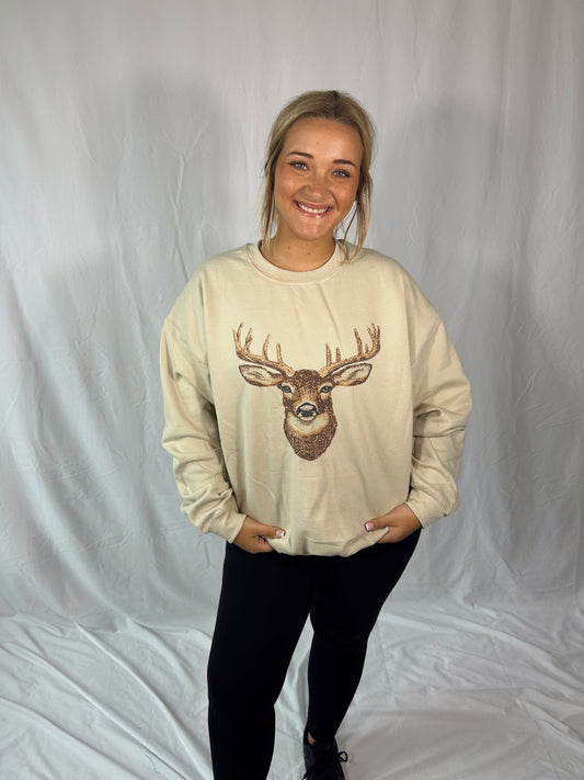 Person wearing a beige sweatshirt with a deer graphic on a plain background